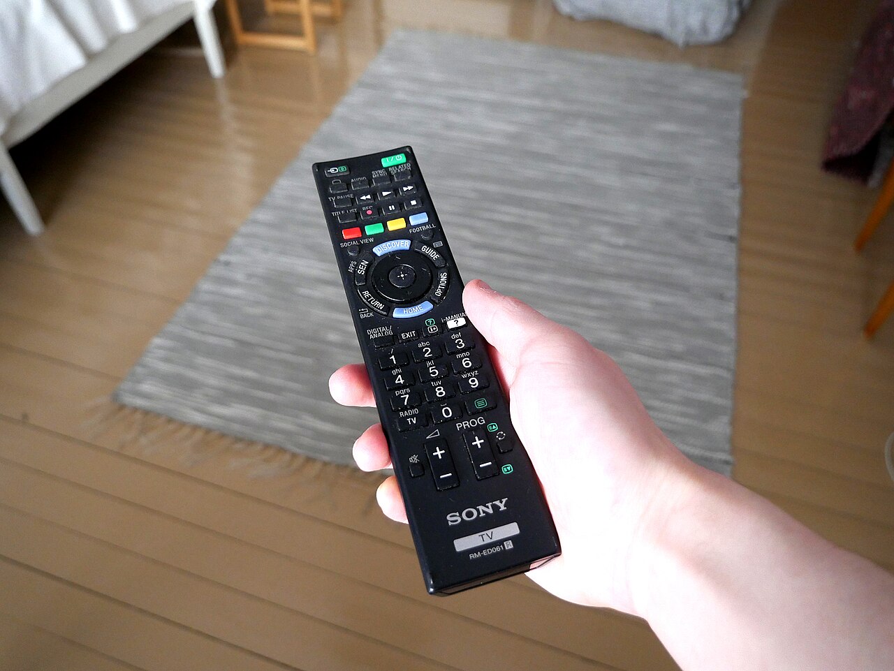 A hand holding a TV remote control, illustrating how streaming platforms are restricting password sharing and changing who can watch on a single account